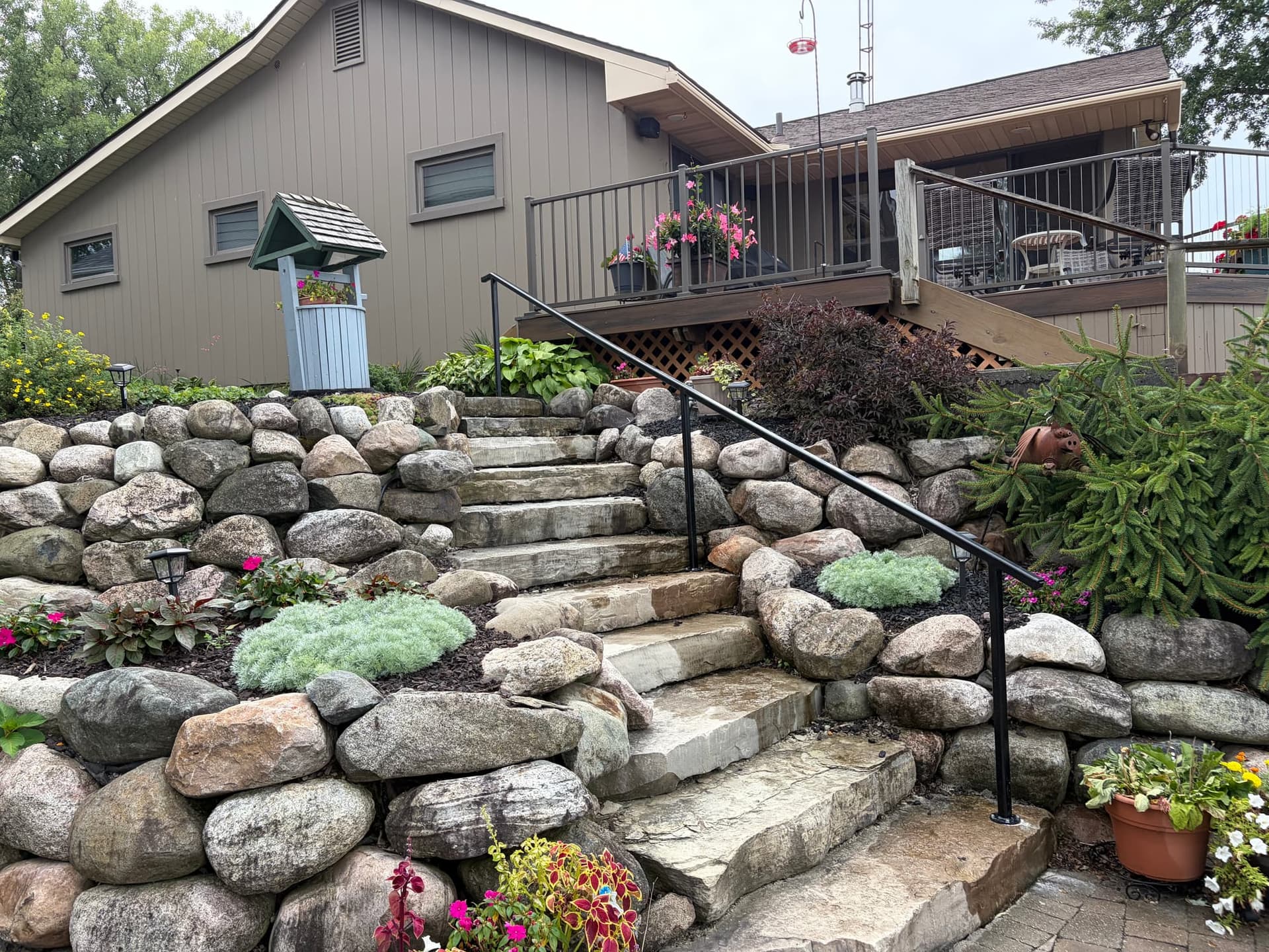 Black steel handrail running the full flight of a natural-stone garden stairway in South Lyon
